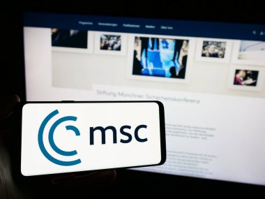 Stuttgart, Almanya - 03-06-2024: Yıllık Münih Güvenlik Konferansı (MSC) logosu olan cep telefonu sahibi kişi web sayfası önünde. Telefon ekranına odaklan.