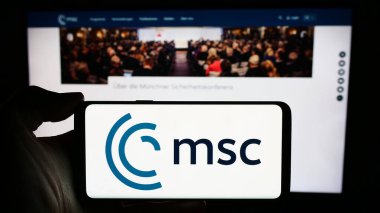 Stuttgart, Almanya - 03-06-2024: Yıllık Münih Güvenlik Konferansı (MSC) logosu olan cep telefonu sahibi kişi web sayfası önünde. Telefon ekranına odaklan.