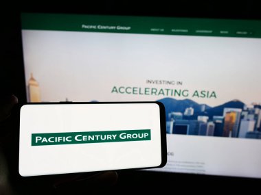 Stuttgart, Almanya - 03-07-2024: Yatırım şirketi Pacific Century Group 'un (PCG) logosuna sahip akıllı telefon sahibi kişi web sitesi önünde. Telefon ekranına odaklan.