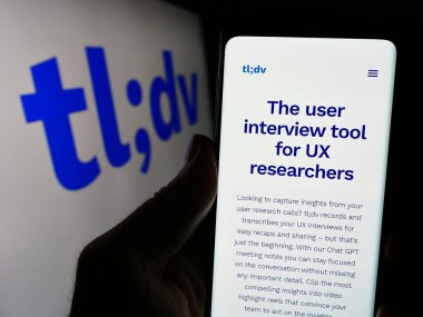 Stuttgart, Almanya - 03-08-2024: İş logosu önünde Alman yapay zeka toplantı asistanı TI; dv 'nin web sayfası ile cep telefonu tutan kişi. Telefon ekranının merkezine odaklan.