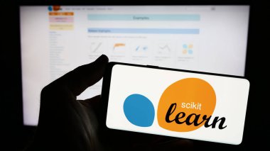 Stuttgart, Almanya - 03-08-2024: İnternet sitesi önünde üzerinde yazılım makinesi logosu olan akıllı telefon tutan kişi. Telefon ekranına odaklan.
