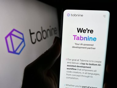 Stuttgart, Almanya - 03-08-2024: İsrail AI kodlama şirketi Tabnine Ltd. 'nin internet sayfası ile iş logosu önünde cep telefonu tutan kişi. Telefon ekranının merkezine odaklan.