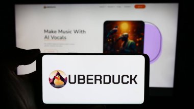 Stuttgart, Almanya - 03-08-2024: İnternet sayfası önünde üzerinde ABD 'li yapay zeka müzik şirketi Uberduck Inc.' in logosu bulunan kişi. Telefon ekranına odaklan.