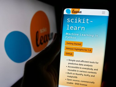 Stuttgart, Almanya - 03-08-2024: Yazılım makinesinin web sayfası ile cep telefonu tutan kişi logo önünde scikit-learn öğreniyor. Telefon ekranının merkezine odaklan.