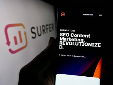 Stuttgart, Almanya - 03-08-2024: Polonyalı yapay zeka şirketi Surfer sp 'nin web sayfası ile cep telefonu tutan kişi. - Hoşça kal. (Sörfçü) Logonun önünde. Telefon ekranının merkezine odaklan.