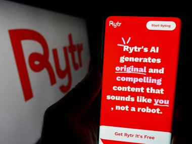 Stuttgart, Almanya - 03-10-2024: ABD 'li yapay zeka yazma aracı şirketi Rytr LLC' nin logolu web sayfası ile akıllı telefon tutan kişi. Telefon ekranının merkezine odaklan.