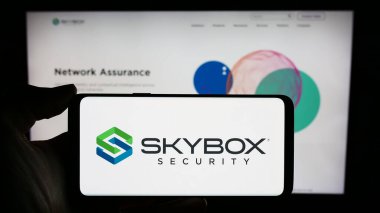 Stuttgart, Almanya - 03-10-2024: Üzerinde ABD 'li siber güvenlik şirketi Skybox Security Inc.' in logosu bulunan cep telefonu sahibi kişi iş sayfasının önünde. Telefon ekranına odaklan.