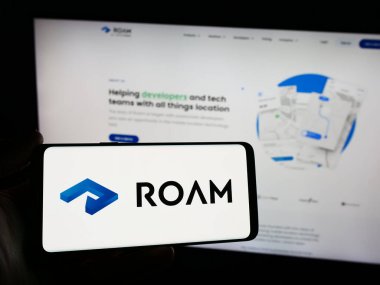Stuttgart, Almanya - 03-10-2024: Hollandalı konum izleme şirketi Roam.ai 'nin logosuna sahip akıllı telefon sahibi kişi web sitesinin önünde. Telefon ekranına odaklan.