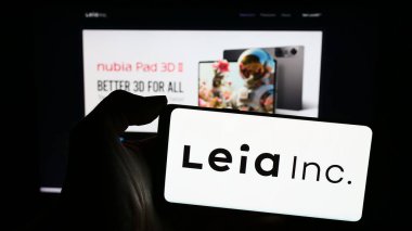 Stuttgart, Germany - 03-12-2024: Person holding smartphone with logo of US 3D display company Leia Inc. in front of website. Focus on phone display. clipart