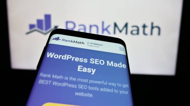 Stuttgart, Almanya - 03-12-2024: Indian WordPress SEO şirketi Rank Math 'in web sitesiyle birlikte iş logosu önünde cep telefonu. Telefon ekranının sol üst kısmına odaklan.