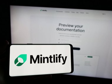 Stuttgart, Almanya - 03-13-2024: Web sitesi önünde üzerinde ABD 'li belge platformu şirketi Mintlify Inc.' in logosu bulunan akıllı telefon sahibi kişi. Telefon ekranına odaklan.