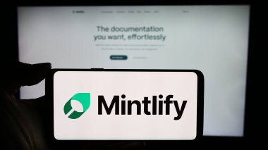 Stuttgart, Almanya - 03-13-2024: ABD 'li belgelendirme platformu şirketi Mintlify Inc.' in logosuyla cep telefonu tutan kişi iş sayfasının önünde. Telefon ekranına odaklan.