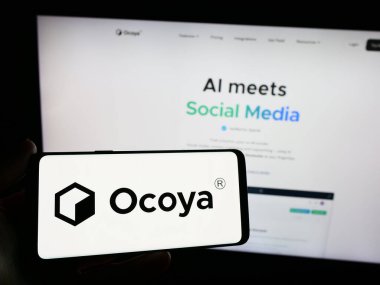 Stuttgart, Almanya - 03-13-2024: Litvanyalı yapay zeka şirketi Ocoya 'nın logosuna sahip akıllı telefon sahibi kişi web sitesinin önünde. Telefon ekranına odaklan.