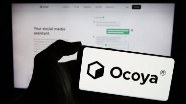 Stuttgart, Almanya - 03-13-2024: Litvanyalı yapay zeka şirketi Ocoya 'nın logosuyla cep telefonu tutan kişi iş sayfasının önünde. Telefon ekranına odaklan.