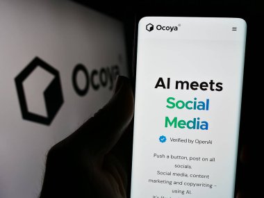 Stuttgart, Almanya - 03-13-2024: Litvanyalı yapay zeka şirketi Ocoya 'nın internet sayfası ile logo önünde cep telefonu tutan kişi. Telefon ekranının merkezine odaklan.