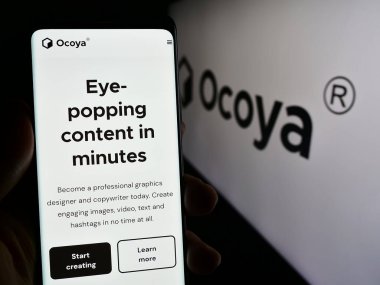Stuttgart, Almanya - 03-13-2024: Litvanyalı yapay zeka şirketi Ocoya 'nın internet sayfası ile logo önünde akıllı telefon tutan kişi. Telefon ekranının merkezine odaklan.