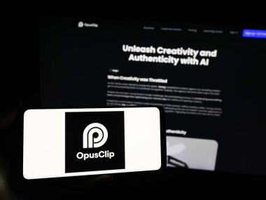 Stuttgart, Almanya - 03-13-2024: İnternet sitesi önünde yapay zeka video düzenleme şirketi Opus Clip 'in logosuna sahip kişi. Telefon ekranına odaklan.