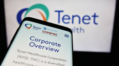 Stuttgart, Germany - 03-13-2024: Mobile phone with website of US health services company Tenet Healthcare Corporation in front of logo. Focus on top-left of phone display. clipart