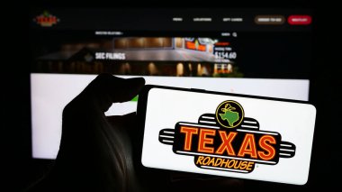 Stuttgart, Almanya - 03-13-2024: İnternet sitesinin önünde ABD 'li biftek lokantası şirketi Texas Roadhouse Inc.' in logosu olan akıllı telefon sahibi kişi. Telefon ekranına odaklan.
