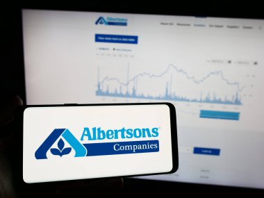 Stuttgart, Almanya - 03-13-2024: İnternet sayfası önünde üzerinde Amerikan market perakende şirketi Albertsons Company 'nin logosu bulunan cep telefonu sahibi kişi. Telefon ekranına odaklan.