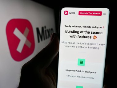 Stuttgart, Almanya - 03-13-2024: İş logosu önünde AI web sitesi inşa şirketi Mixo 'nun web sayfası ile cep telefonu tutan kişi. Telefon ekranının merkezine odaklan.