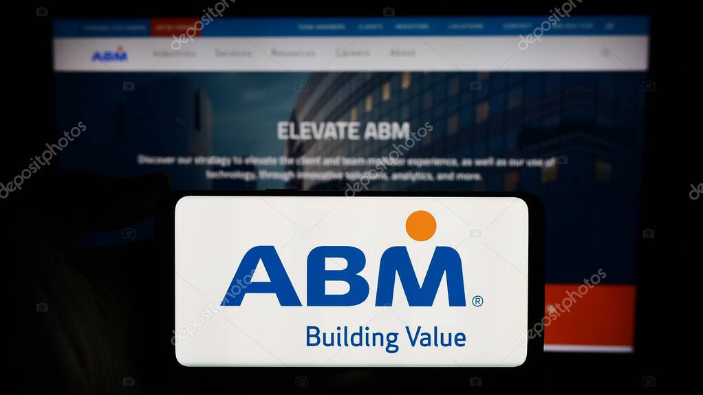 Stuttgart, Germany - 03-13-2024: Person holding cellphone with logo of US facility management company ABM Industries Inc. in front of business webpage. Focus on phone display.
