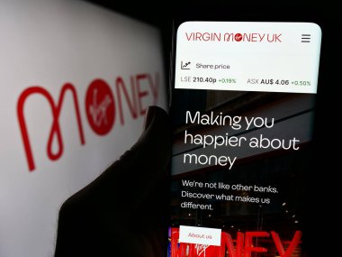 Stuttgart, Almanya - 03-18-2024: İngiliz finans hizmetleri şirketi Virgin Money 'nin web sitesi ile logo önünde cep telefonu tutan kişi. Telefon ekranının merkezine odaklan.