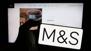 Stuttgart, Almanya - 03-18-2024: İngiliz perakende şirketi Marks ve Spencer Group plc 'in logosunun bulunduğu cep telefonu sahibi kişi iş sayfasının önünde. Telefon ekranına odaklan.