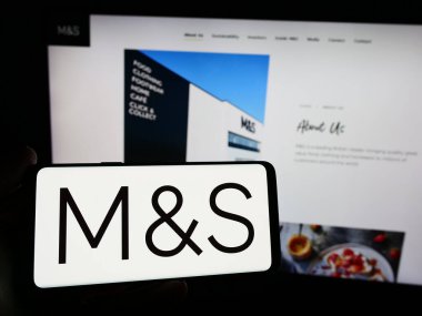 Stuttgart, Almanya - 03-18-2024: İngiliz perakende şirketi Marks ve Spencer Group plc 'in logosuna sahip akıllı telefon sahibi kişi web sitesinin önünde. Telefon ekranına odaklan.