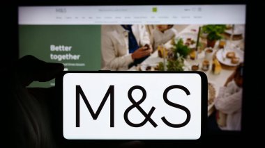 Stuttgart, Almanya - 03-18-2024: İngiliz perakende şirketi Marks ve Spencer Group plc 'in logosuyla cep telefonu sahibi kişi iş sayfası önünde. Telefon ekranına odaklan.