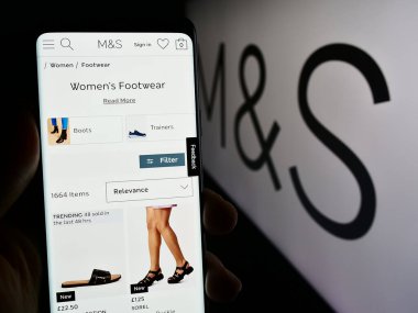 Stuttgart, Almanya - 03-18-2024: İngiliz perakende şirketi Marks ve Spencer Group plc 'in logolu web sayfası ile cep telefonu tutan kişi. Telefon ekranının merkezine odaklan.