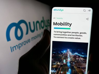 Stuttgart, Almanya - 03-18-2024: İtalyan altyapı şirketi Mundys SpA 'nın web sitesi ile logo önünde akıllı telefon tutan kişi. Telefon ekranının merkezine odaklan.