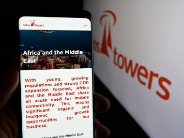 Stuttgart, Almanya - 03-19-2024: İngiliz telekomünikasyon kulesi şirketi Helios Towers 'ın logolu web sayfası ile akıllı telefon tutan kişi. Telefon ekranının merkezine odaklan.