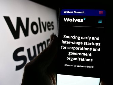 Stuttgart, Almanya - 03-19-2024: Şirket logosu önünde dijital pazarlama platformu Wolves Zirvesi web sitesi ile cep telefonu tutan kişi. Telefon ekranının merkezine odaklan.