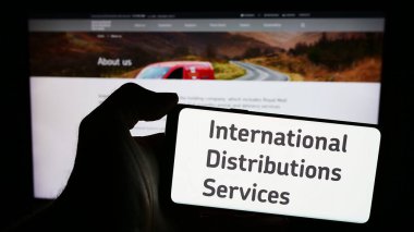 Stuttgart, Almanya - 03-20-2024: İngiliz firması International Distributions Services plc 'in logosunun bulunduğu cep telefonu web sayfası önünde duruyor. Telefon ekranına odaklan.