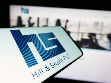 Stuttgart, Germany - 03-20-2024: Mobile phone with logo of British infrastructure company Hill and Smith plc in front of business website. Focus on center-left of phone display. clipart