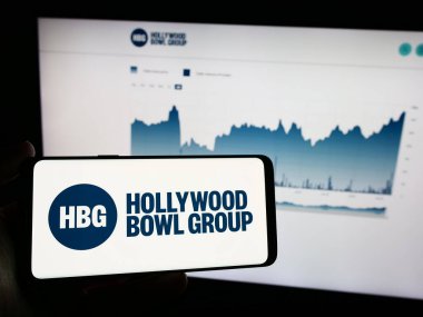 Stuttgart, Almanya - 03-20-2024: İngiliz bowling şirketi Hollywood Bowl Group plc 'un logosunu taşıyan cep telefonu sahibi iş sayfası önünde. Telefon ekranına odaklan.