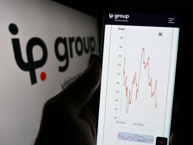 Stuttgart, Almanya - 03-23-2024: İngiliz fikri mülkiyet şirketi IP Group plc 'nin web sitesi ile logo önünde cep telefonu tutan kişi. Telefon ekranının merkezine odaklan.