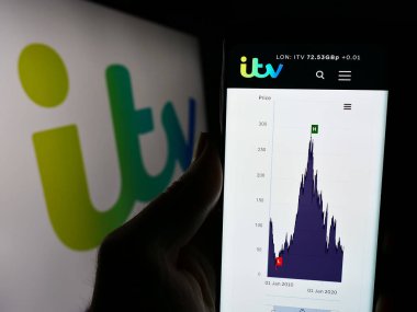 Stuttgart, Almanya - 03-23-2024: İngiliz medyasının web sitesi ve yayın şirketi ITV plc ile logo önünde cep telefonu tutan kişi. Telefon ekranının merkezine odaklan.