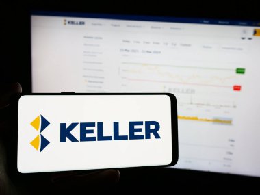 Stuttgart, Almanya - 03-23-2024: Üzerinde jeoteknik mühendislik şirketi Keller Group plc 'nin logosu olan cep telefonu bulunduran kişi iş sayfasının önünde. Telefon ekranına odaklan.