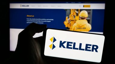 Stuttgart, Almanya - 03-23-2024: İnternet sitesi önünde üzerinde jeoteknik mühendisliği şirketi Keller Group plc 'nin logosu bulunan akıllı telefon sahibi kişi. Telefon ekranına odaklan.