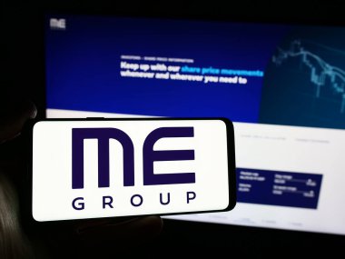 Stuttgart, Almanya - 03-25-2024: İngiliz otomat şirketi ME Group International plc 'nin logosuna sahip akıllı telefon sahibi kişi web sitesinin önünde. Telefon ekranına odaklan.