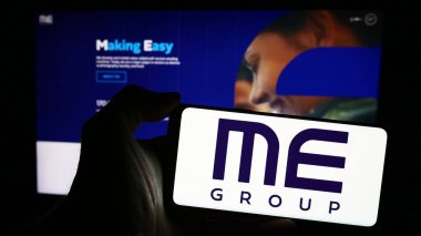 Stuttgart, Almanya - 03-25-2024: İngiliz otomat şirketi ME Group International plc 'nin logosunun bulunduğu cep telefonu sahibi kişi web sayfasının önünde. Telefon ekranına odaklan.
