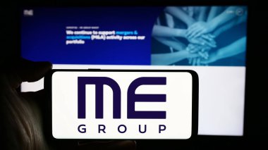 Stuttgart, Almanya - 03-25-2024: İngiliz otomat şirketi ME Group International plc 'nin logosuyla cep telefonu tutan kişi web sayfasının önünde. Telefon ekranına odaklan.