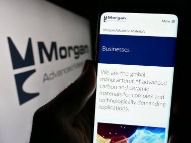 Stuttgart, Almanya - 03-25-2024: İngiliz şirketi Morgan Advanced Materials plc 'in web sayfası ile logo önünde cep telefonu tutan kişi. Telefon ekranının merkezine odaklan.