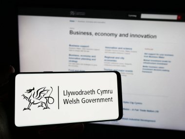 Stuttgart, Almanya - 03-25-2024: İnternet sitesi önünde üzerinde Galler Hükümeti (Llywodraeth Cymru) logosu bulunan kişi. Telefon ekranına odaklan.