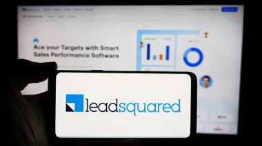 Stuttgart, Almanya - 03-27-2024: Üzerinde Hint CRM platform şirketi LeadSquared 'in logosu bulunan cep telefonu sahibi kişi iş sayfasının önünde. Telefon ekranına odaklan.