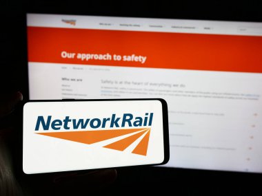 Stuttgart, Almanya - 03-27-2024: İnternet sitesi önünde demiryolu altyapı şirketi Network Rail Limited 'in logosuna sahip akıllı telefon sahibi kişi. Telefon ekranına odaklan.