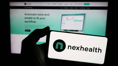 Stuttgart, Almanya - 03-28-2024: İnternet sitesi önünde ABD 'li sağlık yazılım şirketi NexHealth Inc.' in logosuna sahip kişi. Telefon ekranına odaklan.
