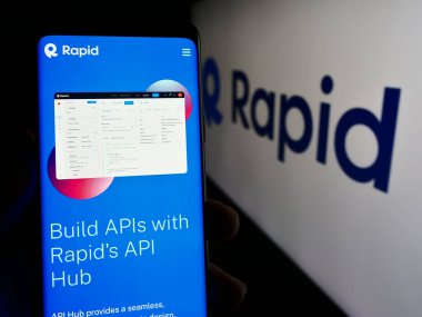 Stuttgart, Almanya - 03-28-2024: ABD API merkez şirketi R Software Inc. (RapidAPI) 'nin web sayfası olan akıllı telefon sahibi kişi logonun önünde. Telefon ekranının merkezine odaklan.
